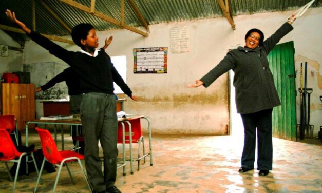 A teacher and pupils with arms spread wide