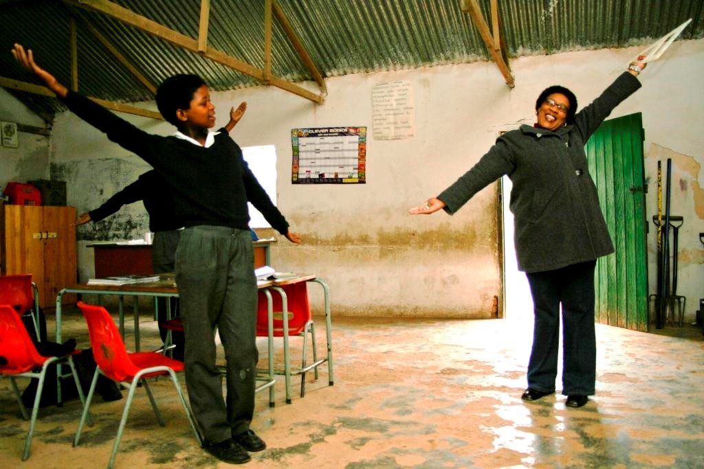 A teacher and pupils with arms spread wide