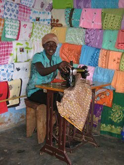 A man at a sewing machine with coloured fabrics