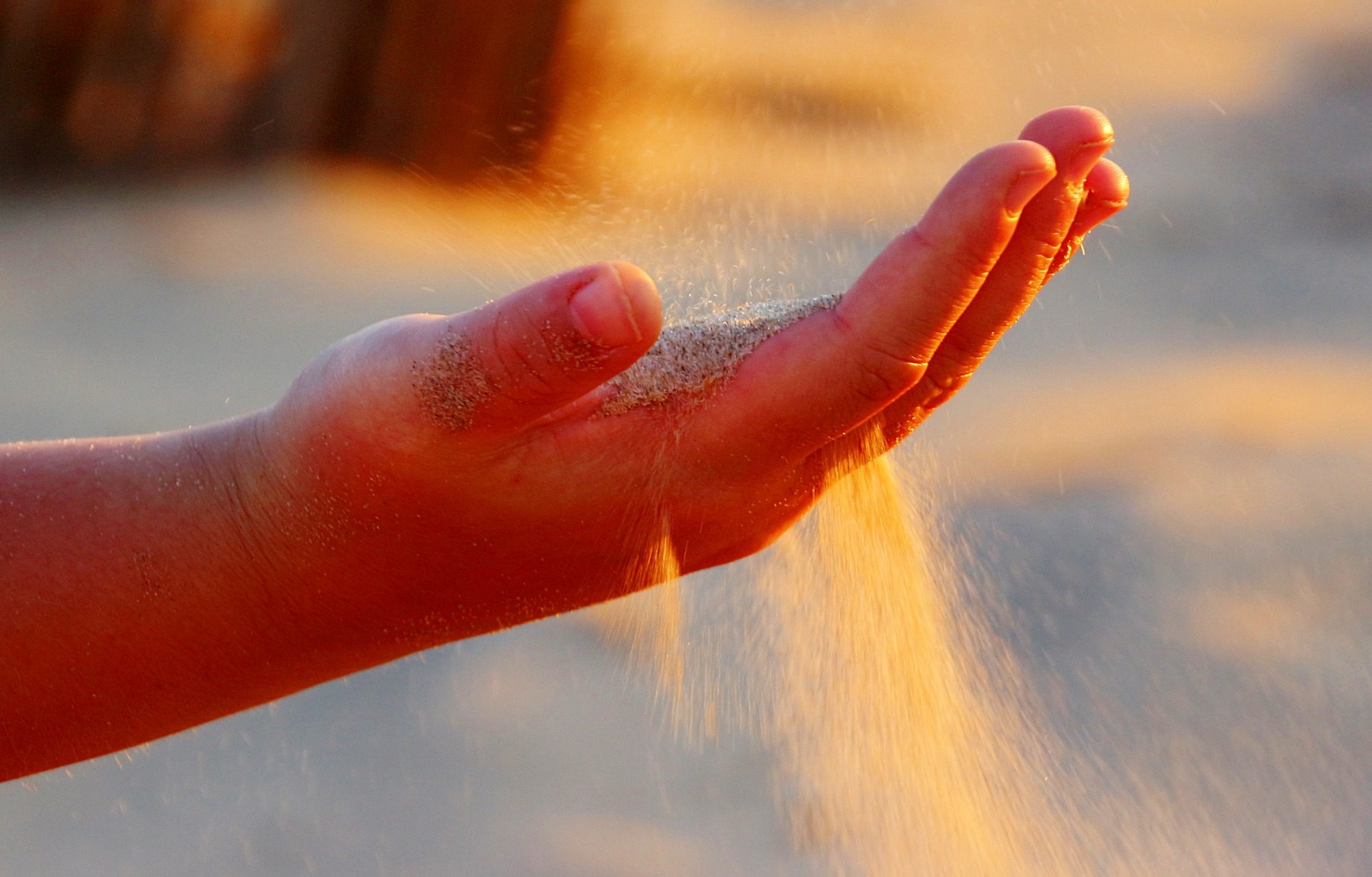 A hand with sand running through the fingers