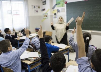 teacher in classroom with students with their hands up