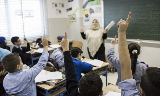 teacher in classroom with students with their hands up