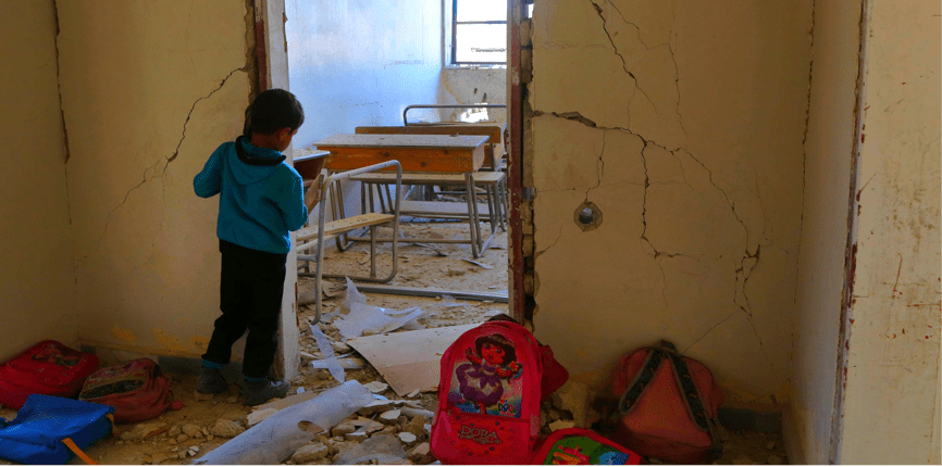 A Syrian child looks into a school classroom damaged during a reported air strike on March 7, 2017, in the opposition-held town of Utaya, near the city of Damascus.
