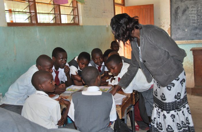 Teacher working with a group of pupils gathered around a table