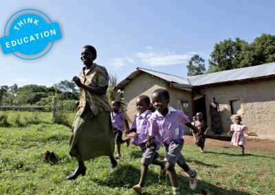 Think Education. Teacher and pupils running outside a school building
