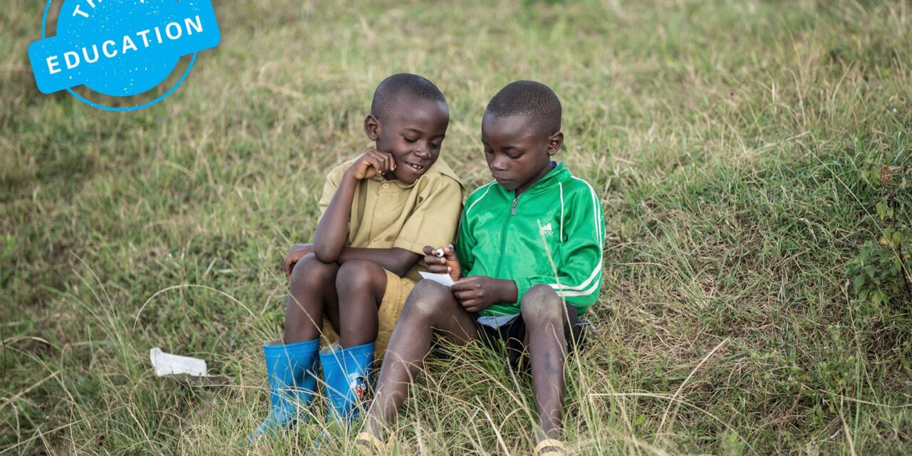 Think Education. Two boys sitting in a field writing