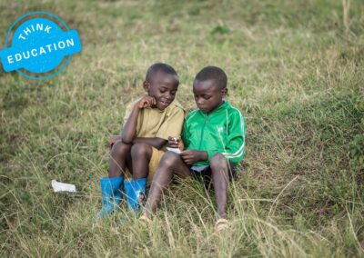 Think Education. Two boys sitting in a field writing