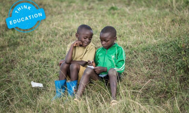 Think Education. Two boys sitting in a field writing