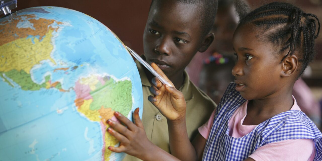 Children looking at a globe of the world in a classroom at school.