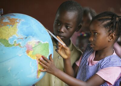 Children looking at a globe of the world in a classroom at school.