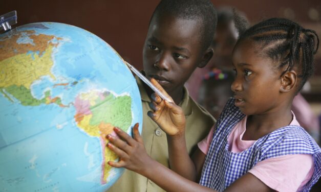 Children looking at a globe of the world in a classroom at school.