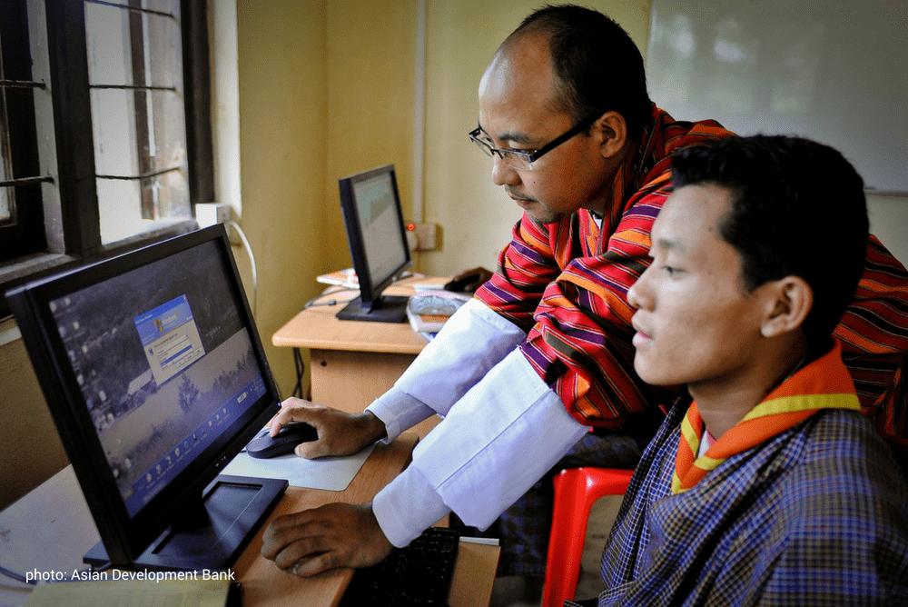 Teacher supporting a pupil at a computer