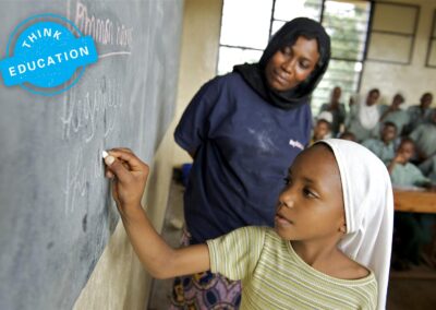 Student writing on a blackboard with teacher