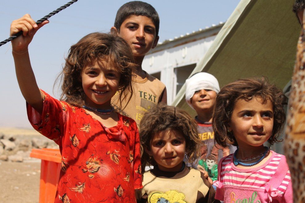 A group of smiling children, one with a bandage around his head