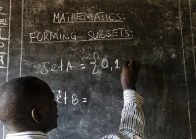 A teacher writes maths formulas on a blackboard at a school. Image Credit_Philippe-Lissac_Godong_Panos-Pictures