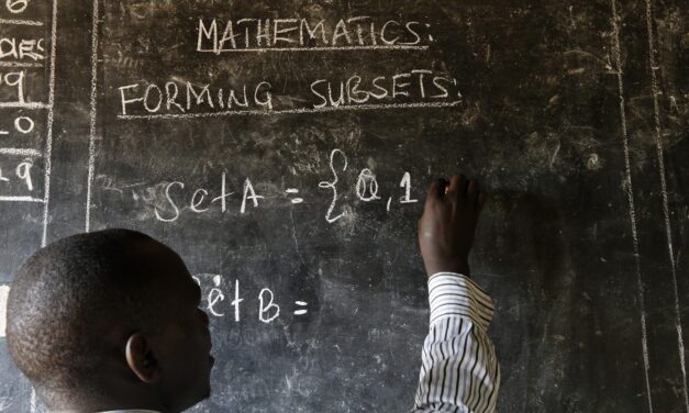 A teacher writes maths formulas on a blackboard at a school. Image Credit_Philippe-Lissac_Godong_Panos-Pictures