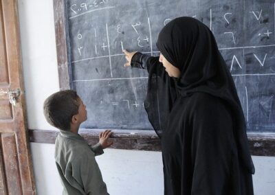 A teacher pointing at the blackboard with a child