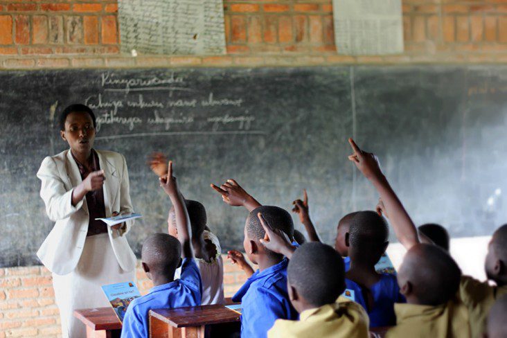 Children in class with hands raised