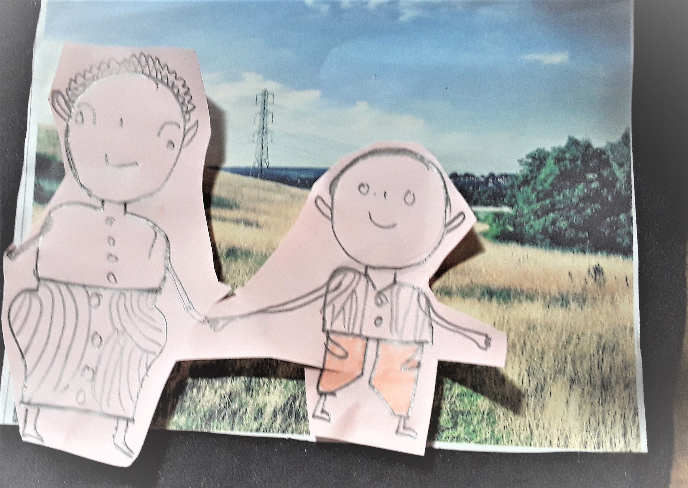 A cut out of a child's drawing of person on top of a photo of fields and a pylon