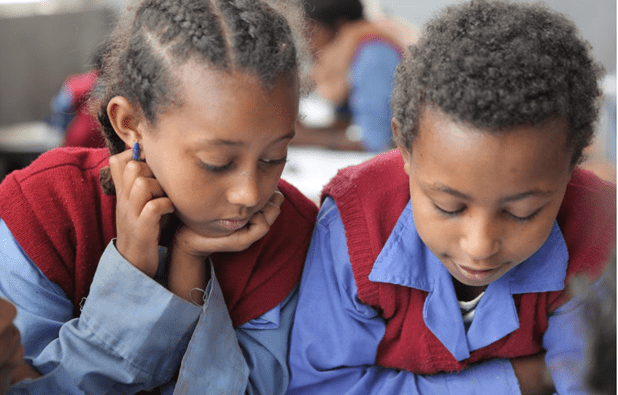 Two primary age pupils looking at their work