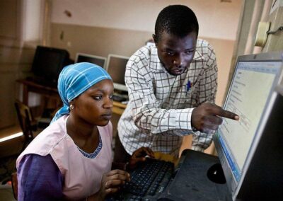 A male pointing at a computer screen with a female seated at the keyboard