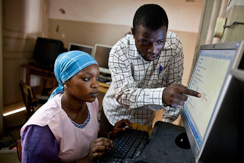 A male pointing at a computer screen with a female seated at the keyboard