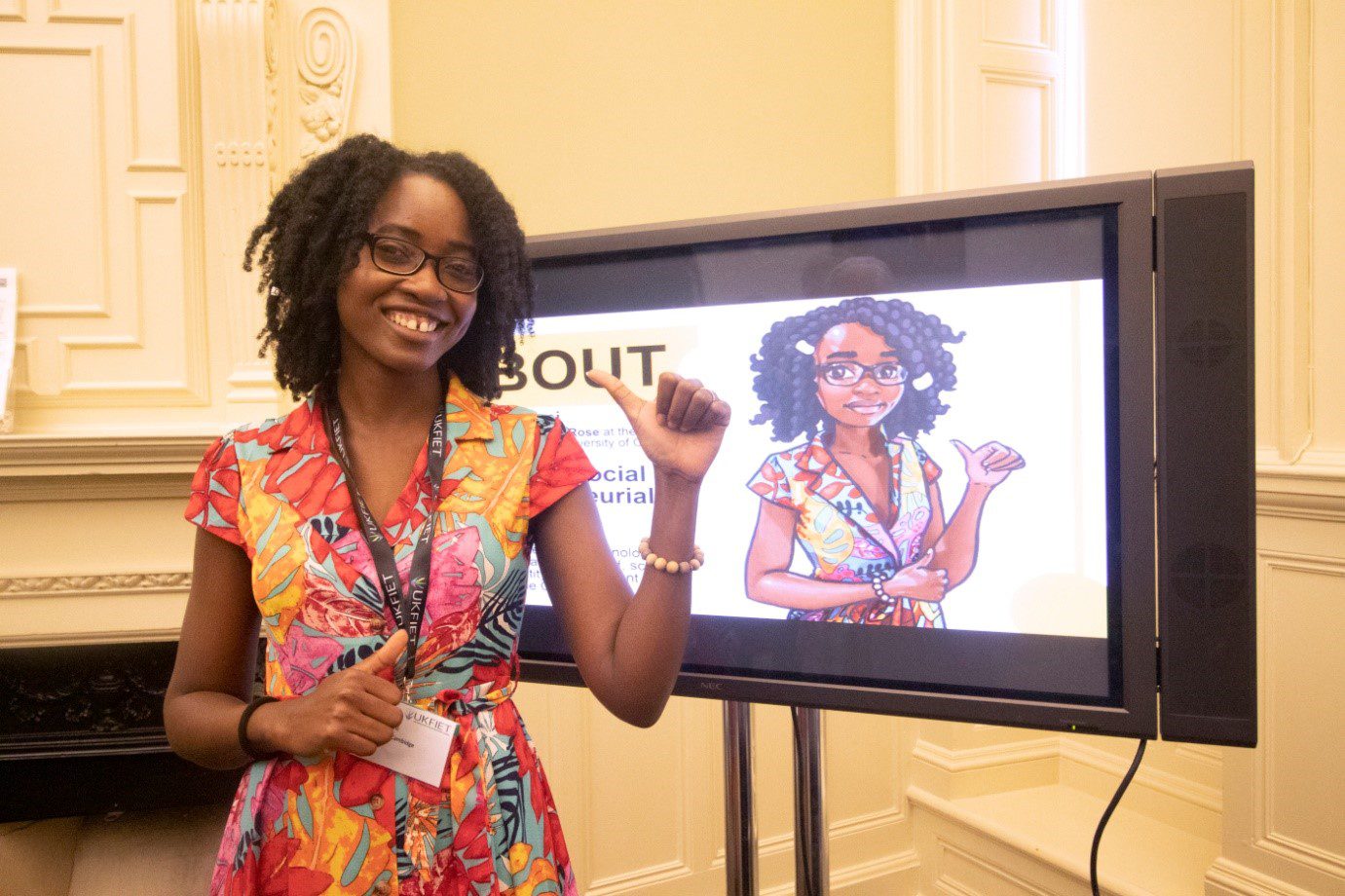 Khalifa standing in front of a screen displaying a caricature of herself at the conference