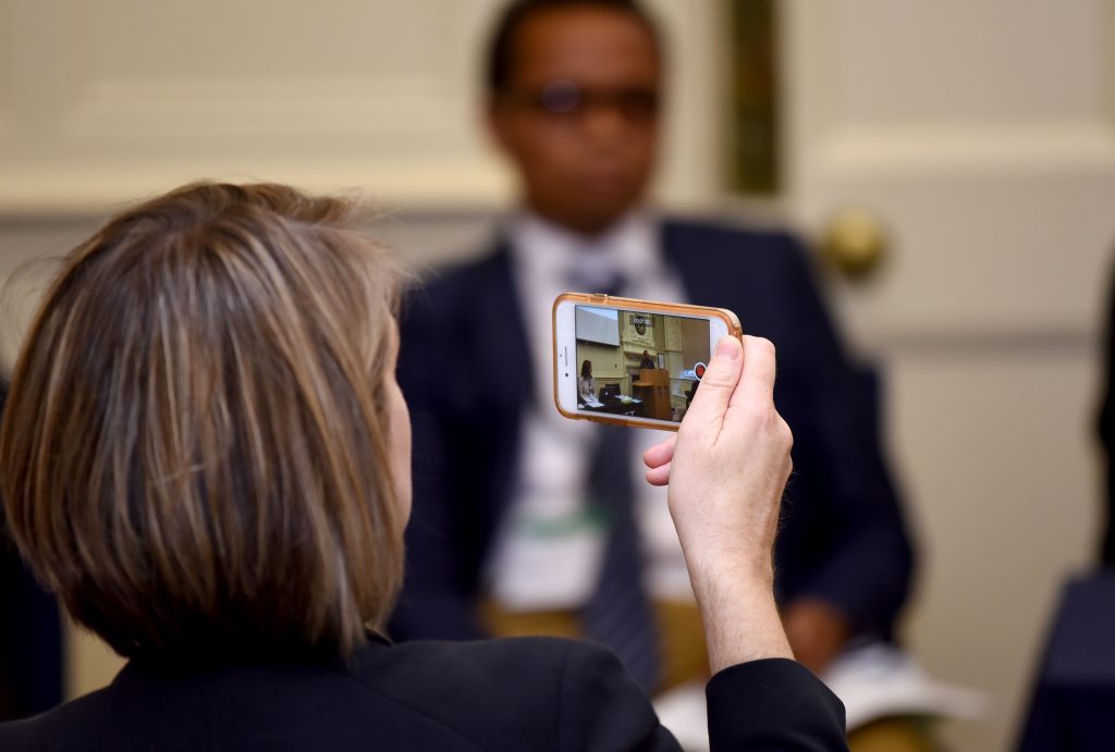 Delegate taking a photo with phone of a presenter in a session