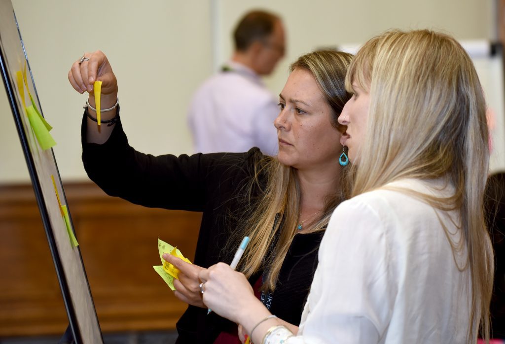 Delegates adding post it notes to a flip chart in a workshop