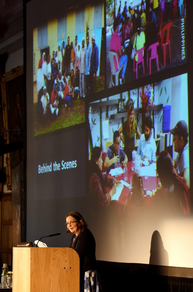 Anna Robinson Pant presenting in front of a large screen of images