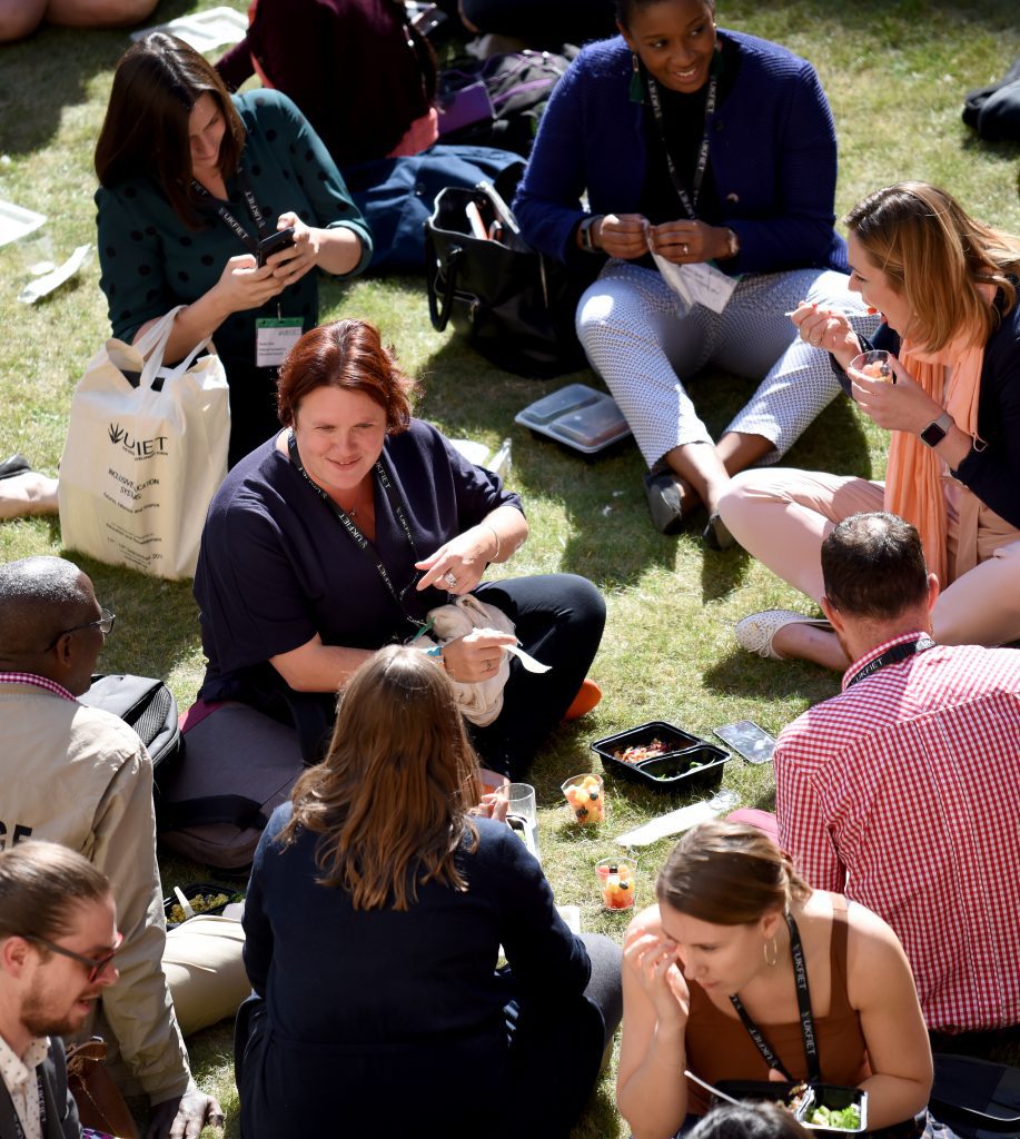 Delegates sitting on the grass in the quod at lunchtime