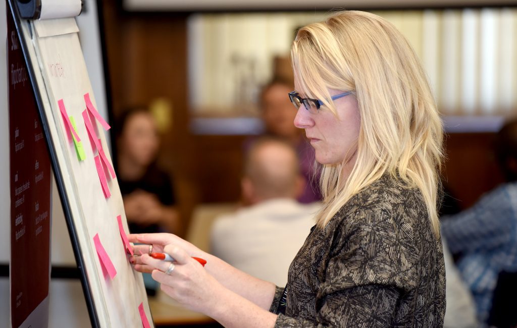 Delegate adding post it notes to a flipchart in a workshop