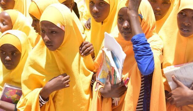 School girls in bright yellow hijabs carrying school books