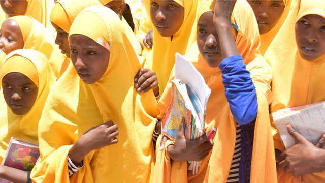 School girls in bright yellow hijabs carrying school books