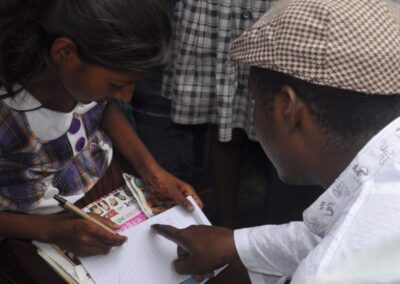 man wearing a flat hat, explaining to a child who is writing