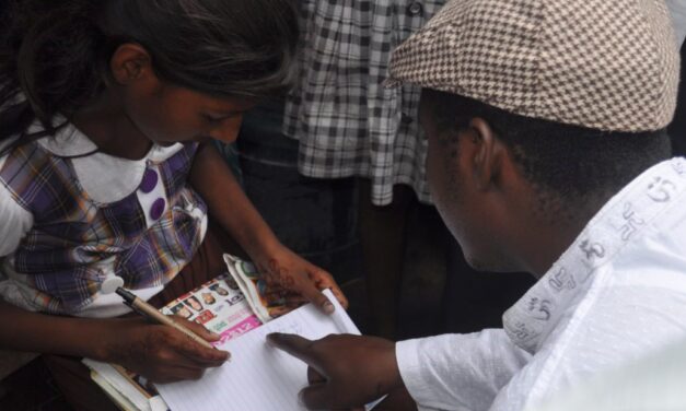 man wearing a flat hat, explaining to a child who is writing