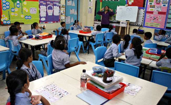 Children in class in India with blue chairs