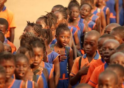 Children waiting in line in a school in Sierra Leone.  Orange and blue uniforms