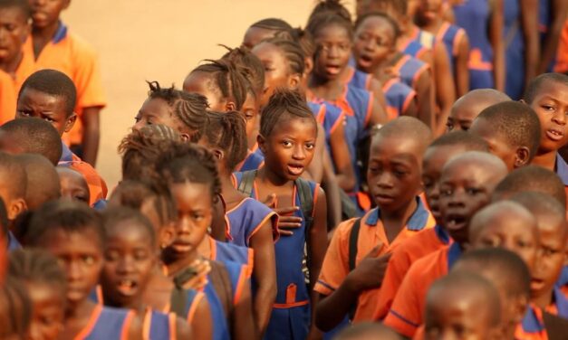 Children waiting in line in a school in Sierra Leone.  Orange and blue uniforms