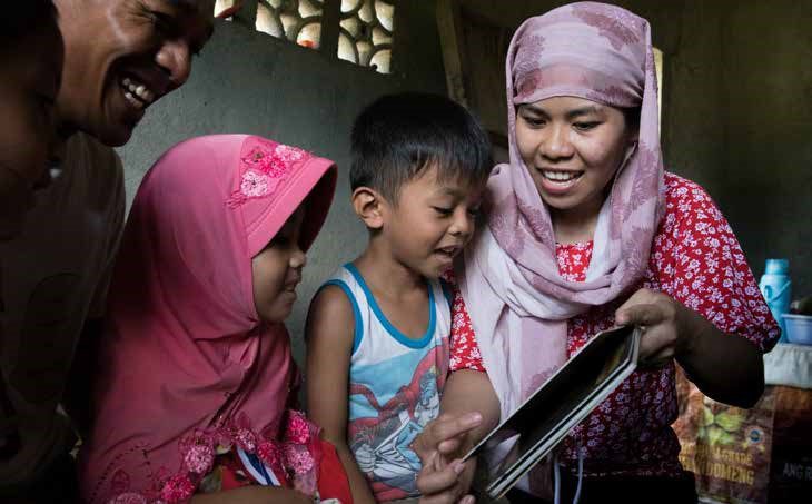  pre primary girl and her family read together at home, in Mindanao, Philippines