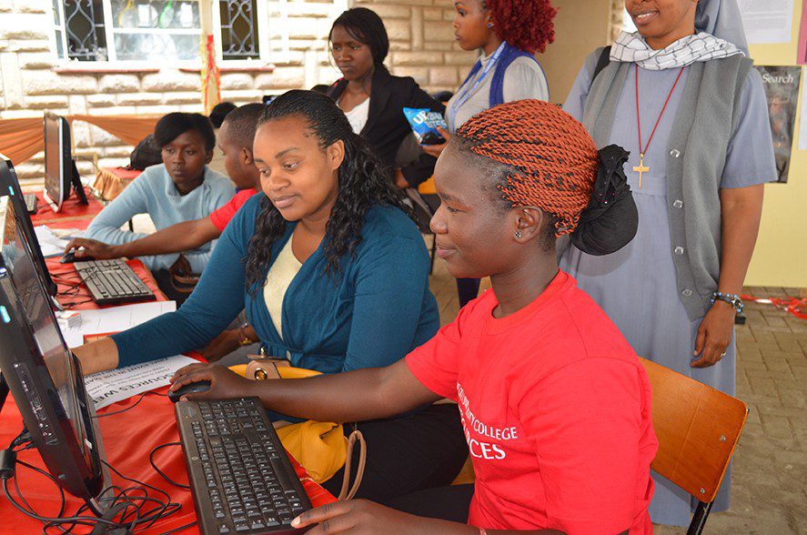 Students working on computers with helpers