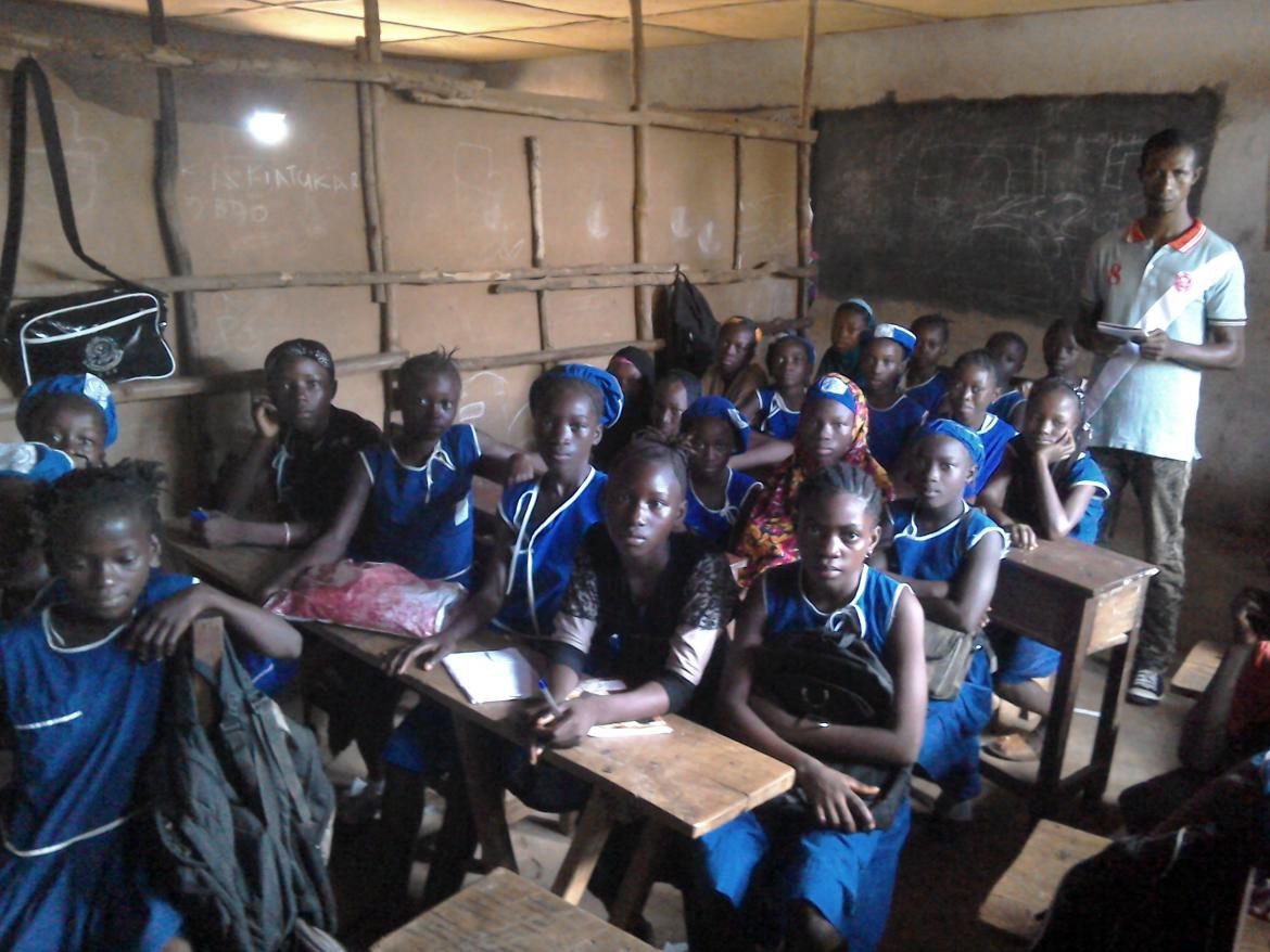 Girls in class in Sierra Leone with teacher standing at the back of the class