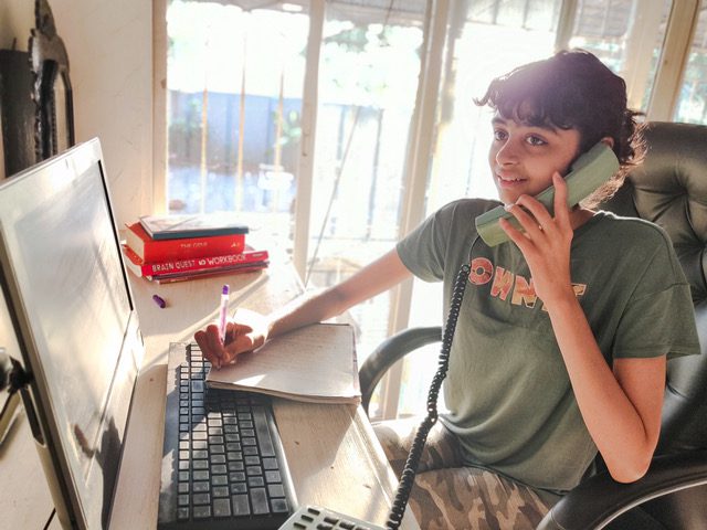 child on telephone sitting at computer screen and keyboard