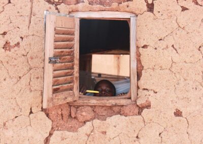 A Ghanaian boy peeks out of the window with his new mosquito net in the background