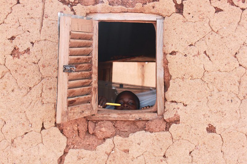 A Ghanaian boy peeks out of the window with his new mosquito net in the background