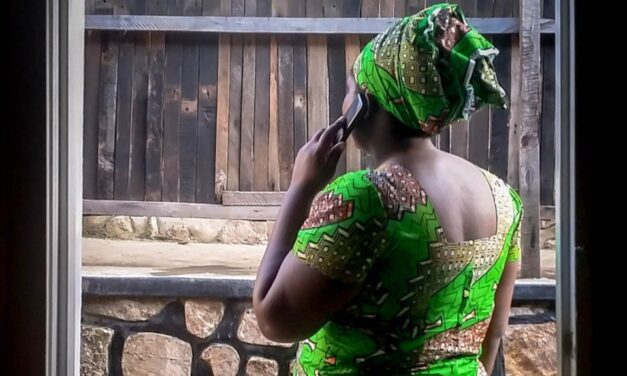 African woman in green dress using a mobile phone