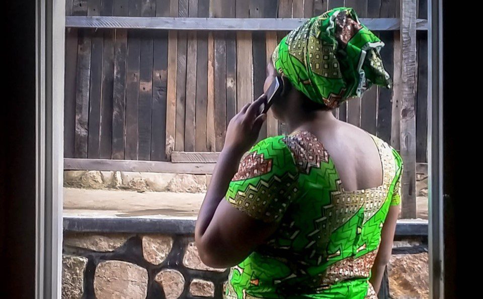 African woman in green dress using a mobile phone
