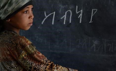 Child by a black board with script