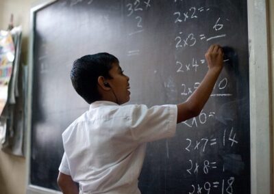 Sri Lankan boy with hearing aids working on maths problem at a classroom blackboard