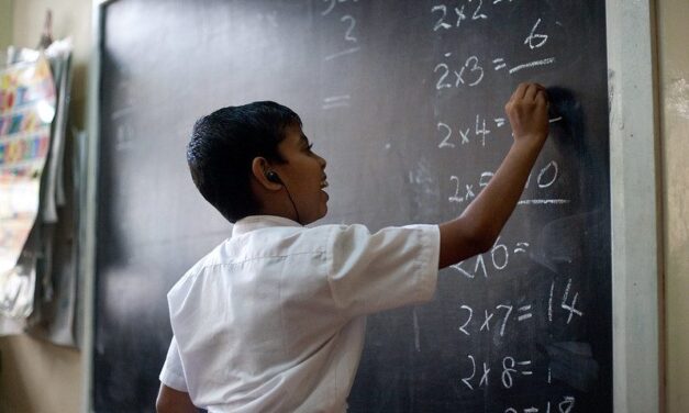 Sri Lankan boy with hearing aids working on maths problem at a classroom blackboard